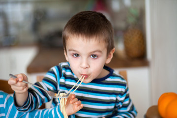 Cute little boy, eating spaghetti at home for lunchtime