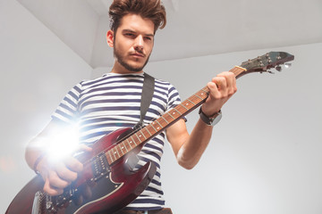 Obraz premium rocker pose looking down while playing the electric guitar