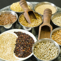 Ancient grains and gluten free seeds in stainless steel containers with wooden scoops