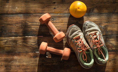 Sneakers, dumbbels and grapefruit on wooden background. Weights for a fitness training.Different tools for fitness training.Sneakers and jumping rope on wooden background - obrazy, fototapety, plakaty