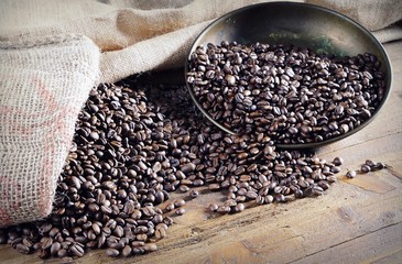 Heap of roasted coffee beans on wooden table