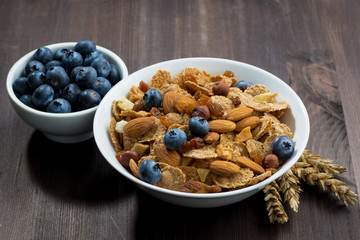 cereal flakes with blueberries and nuts on a dark wooden table
