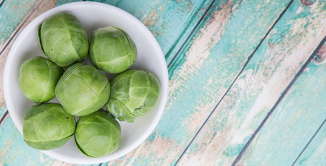 Brussels sprout in white bowl over wooden background