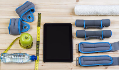 Sport Equipment. Dumbbells,  Ankle Weights, Wrist Weights, Towel, Tape Measure, Apple, Bottle Of Water And Tablet To Workout Plan On Boards. Sport Fitness Background