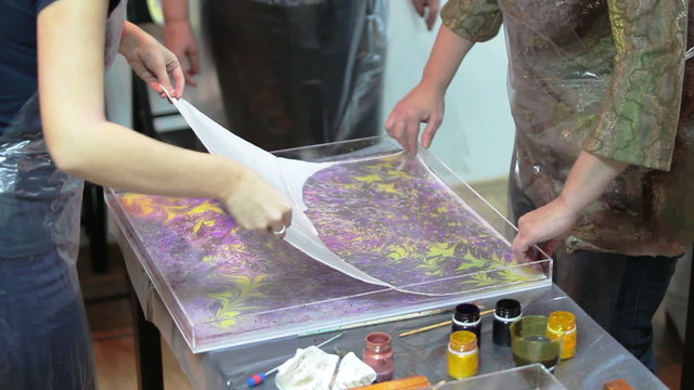 People printing Ebru drawing from water on silk shawl. The Ebru is water marbling art
