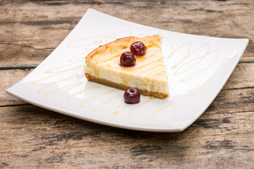 Slice of cheesecake with cherry on white dish