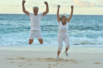Senior couple  jumping on  seashore