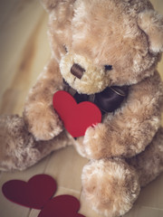 Toy bear with the heart in its hands on the wooden floor