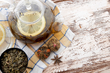 Ripe lemon, cinnamon and fruit drink in glass teapot on wooden background