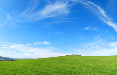 Fototapeta na wymiar Verde e Blu - Collina con dell'erba verde e un cielo azzurro con delle belle nuvole frastagliate