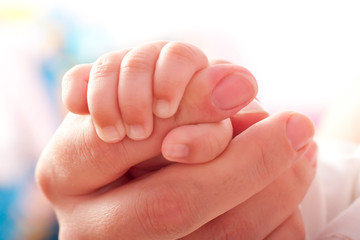 Baby`s fingers on the mother`s hand