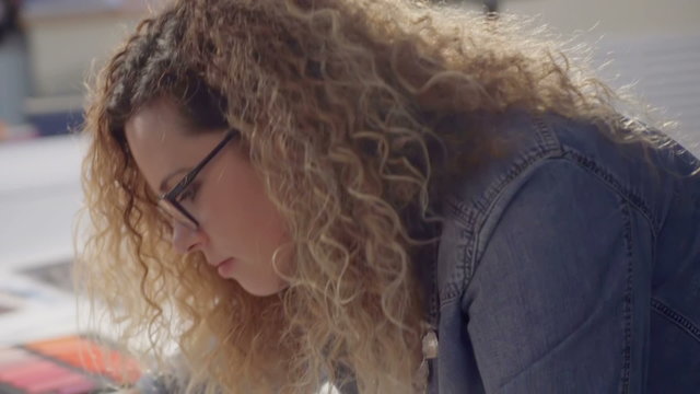 Happy curly girl smiling at the camera. Girl in glasses. The girl the designer or artist illustrator, tailor. Or engage in geometry