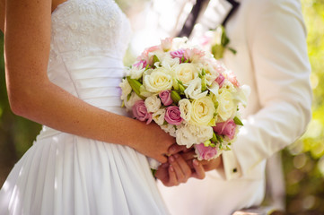 Obraz na płótnie Canvas Wedding Flowers Bouquet in Bride Hands with White Dress on Background