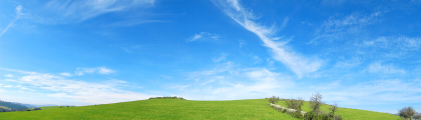 Obraz na płótnie Canvas Verde e Blu - Collina con dell'erba verde e un cielo azzurro con delle belle nuvole frastagliate