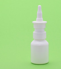 Nasenspray in der Weißen  Plastikflasche isoliert auf grünem Hintergrund 