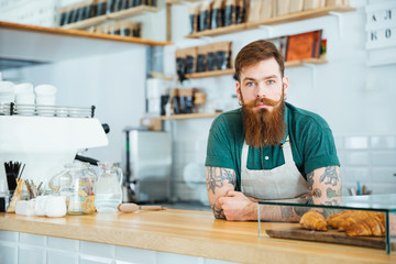 Fototapeta na wymiar Portrait of bearded male barista standing in coffee shop