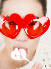 Valentine's day portrait of an attractive young brunette girl with heart shaped glasses and heart...