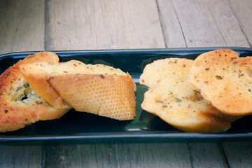 Close-up of a dish of garlic bread on wooden deck table