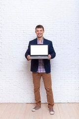 Young Business Man Holding Laptop Screen With Empty Copy Space Stand Over Wall