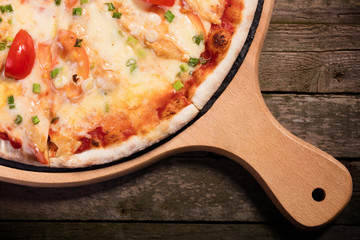 Hot spicy pizza with mozzarella and vegetables served on wood