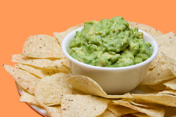 Chips and Guacamole Dip – Crisp corn tortilla chips and fresh guacamole. On a bright orange background.