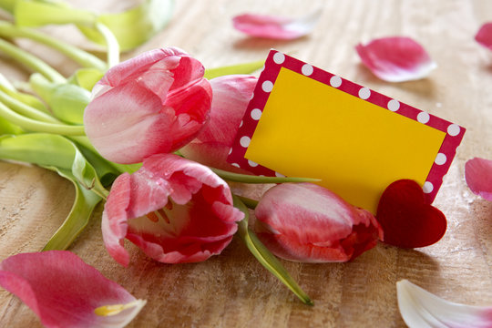 Pink tulips with  card on wood background.