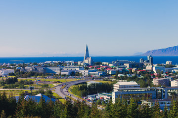 Beautiful super wide-angle aerial view of Reykjavik, Iceland with harbor and skyline mountains and scenery beyond the city, seen from the observation tower of Hallgrimskirkja Cathedral. - obrazy, fototapety, plakaty