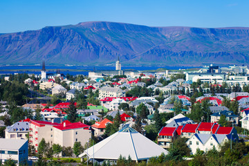 Beautiful super wide-angle aerial view of Reykjavik, Iceland with harbor and skyline mountains and scenery beyond the city, seen from the observation tower of Hallgrimskirkja Cathedral. © tsuguliev