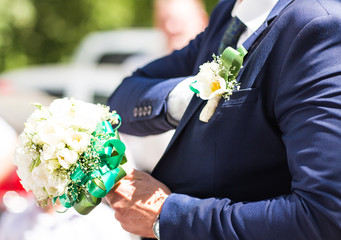 Beautiful wedding bouquet in hands of the groom. Gift to the bride.Blue classic designer suit with  buttonhole.