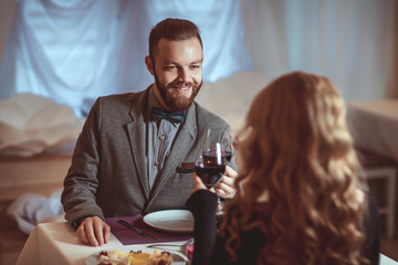 Beautiful young couple with glasses of red wine in luxury restaurant