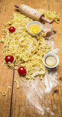 raw tomatoes and pasta with flour, eggs and salt on wooden rustic background top view close up