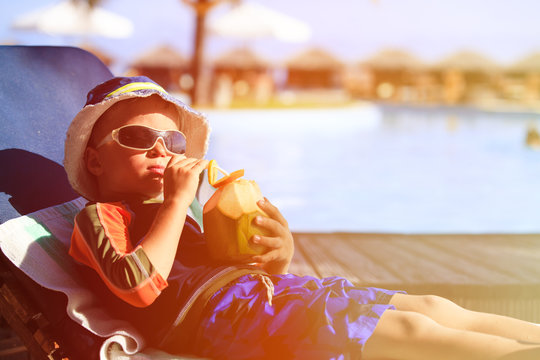 little boy drinking coconut cocktail on tropical beach