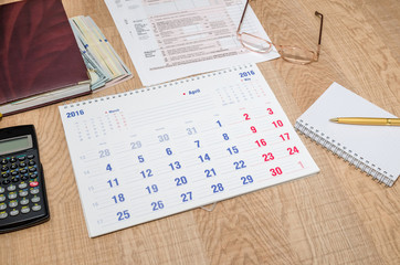Obraz premium paper calendar with dollar, pen, calculator, notepad on table