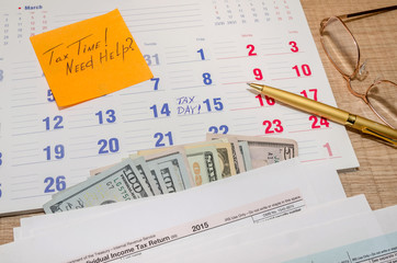 Tax form with calendar, pen, calculator, notepad and glasses