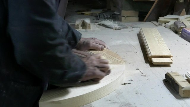 Столяр зачищает поверхность изделия