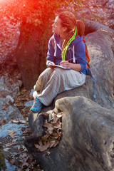 Cute Girl sitting in Forest and drawing sketch in her note book