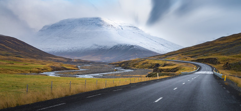 Fototapeta Curve line road surround by yellow field with snow mountain background Autumn season Iceland