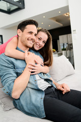 portrait of happy young couple together at home in sofa