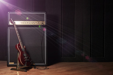 Red electric guitar and classic amplifier on a dark background with lens flare effect