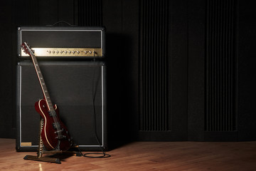 Red electric guitar and classic amplifier on a dark background - Powered by Adobe