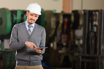 Young businessman posing tablet in factory