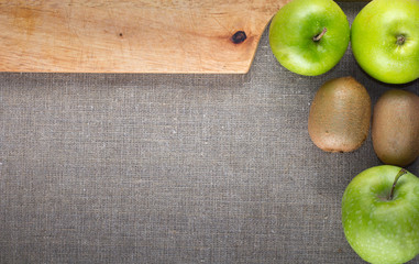 apples, kiwi fruit, cutting board on background