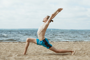 Naked man doing yoga on the beach