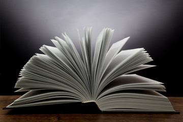 Old open book with light on a dark background