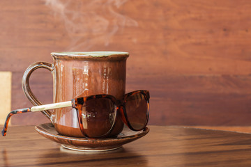 Coffee mug with sunglasses on table