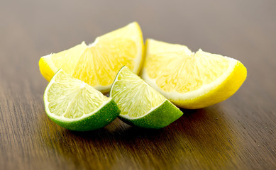 Macro of wedges of limes infront of yellow lemons