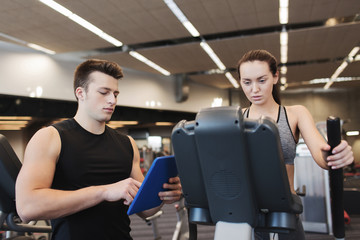 woman with trainer exercising on stepper in gym