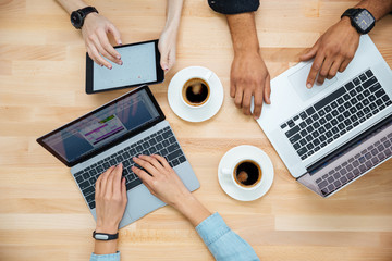 Multiethnic group of young people using laptops and drinking coffee
