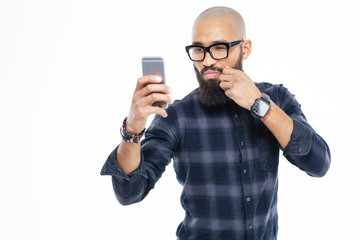 Baldheaded african american man touching moustache and taking selfie