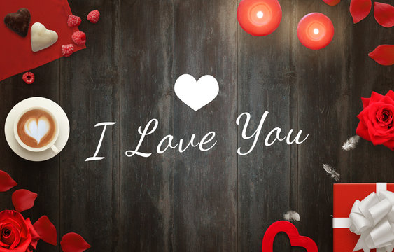 I love you message with coffee, gifts, hearts, candles, roses, petals, sweets on wooden table.